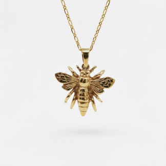 A yellow gold queen bee pendant necklace with textured wings hanging from a fine figaro-style chain against a plain white background.